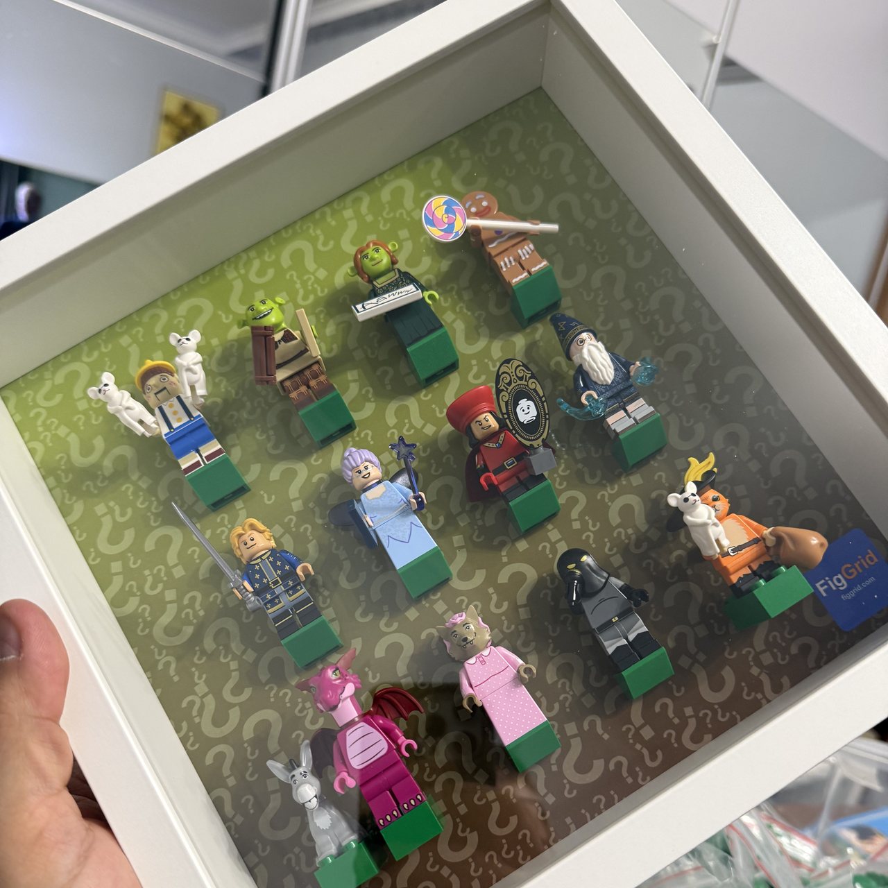 Gotowa ramka 25x25: seria 12 minifigurek na własnym tle z generatora FigGrid, zieleń przechodząca w brąz